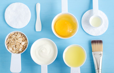 Sour cream (greek yogurt), raw egg, rolled oats and olive oil in a small plastic scoops - ingredients for preparing diy masks, scrubs and moisturizers. Homemade cosmetics. Top view, copy space.
