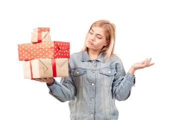 Young blonde in denim jacket holding heap of gift boxes