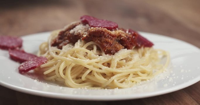 Slow motion closeup fly out shot of fuet falling on spaghetti bolognese