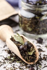 Healthy herbal tea with black currants in a glass jar and wooden scoop. Vitamin drink. Diet. Antioxidant. Selective focus