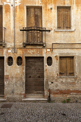 Withered facade with window of an old Italian town house. Cracks in the wall. Byzantine frame.