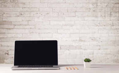 Business laptop with white brick wall