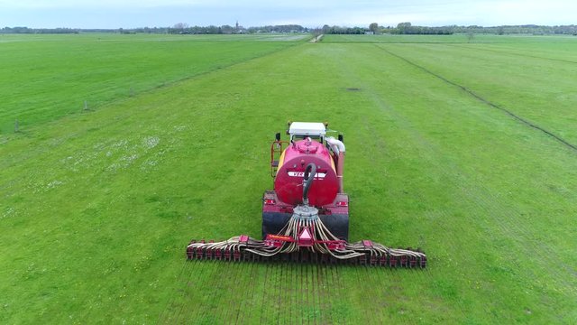 Aerial footage following manure injector large agricultural machine fertilizing grassland injecting manure underground which is used as organic fertilizer in agriculture and better for environment 4k
