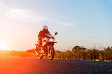 Obraz na płótnie Canvas man riding motorcycle on sunset
