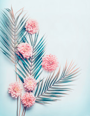 Creative layout with tropical palm leaves and pastel pink flowers on  turquoise blue desktop background, top view, place for text, vertical - obrazy, fototapety, plakaty