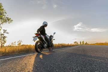 Man on motorcycle on the road during sunset