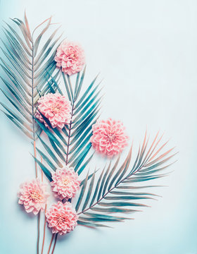 Fototapeta Creative layout with tropical palm leaves and pastel pink flowers on  turquoise blue desktop background, top view, place for text, vertical