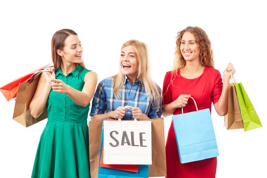 Portrait of three young woman holding bunches of multi-colored shopping bags after sale