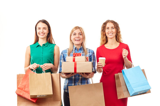 Portrait of three shopaholic girlfriends holding shopping bags and gift boxes