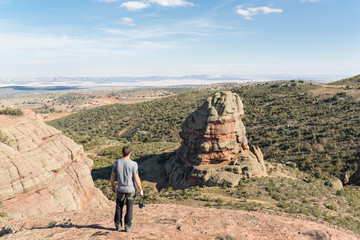 Hombre de pie, mirando a un risco de rodeno en Peracense, Teruel, España