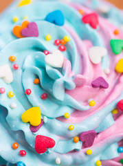 Obraz na płótnie Canvas Closeup cupcake creamy multicolored top with colorful hearts and sprinkles