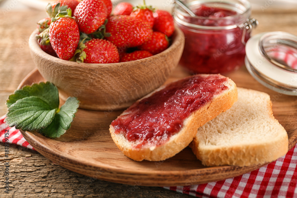 Sticker dish with pieces of bread, jam and strawberries on table