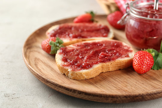 Dish with pieces of bread and strawberry jam on table