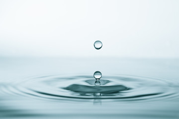 Water drop and splash on water surface on blue background
