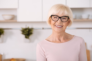 Joyful nice woman standing in the kitchen