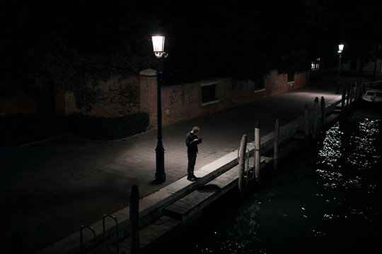 Man standing near streetlight at night
