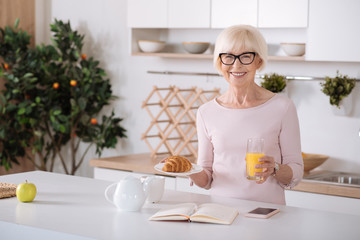 Obraz na płótnie Canvas Joyful senior woman enjoying her breakfast