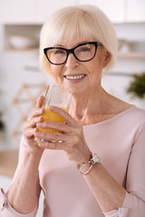 Portrait of a nice elderly woman drinking orange juice
