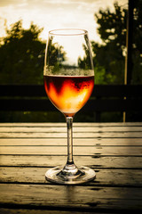 Close-up of wine glass on a table backlit by last light of day
