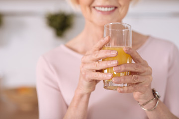 Selective of a orange juice glass in hands of a nice elderly woman