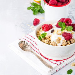 Healthy breakfast with oatmeal granola, berries and yogurt on light gray background. Copy space.