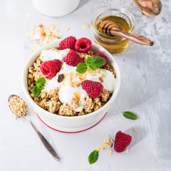 Healthy breakfast with oatmeal granola, berries and yogurt on light gray background.