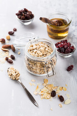 Ingredients for homemade oatmeal granola in glass jar. Oat flakes, honey, raisins and nuts. Healthy breakfast concept with copy space.