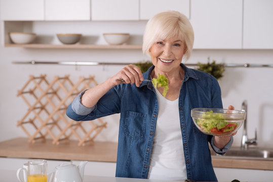Cheerful senior woman eating vegetable salad