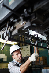 Technician with spanner adjusting parts of modern industrial equipment