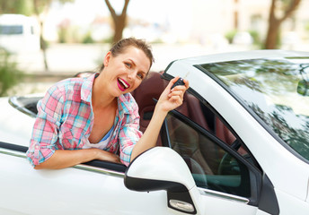 Woman is standing near the convertible car with the keys in hand - concept of buying a used car or a rental car
