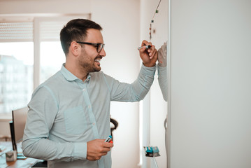 Businessman in the office writing notes on whiteboard.