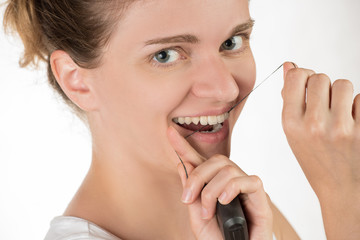 Hygiene of the oral cavity. Young girl cleans teeth with floss, smiling and showing okay sign on background.