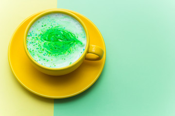 rainbow cappuccino in a bright yellow mug on bright yellow and green background.