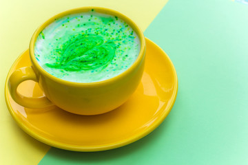 rainbow cappuccino in a bright yellow mug on bright yellow and green background.