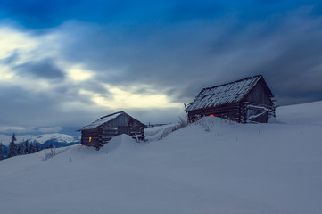 two wooden cabins in winter mountains