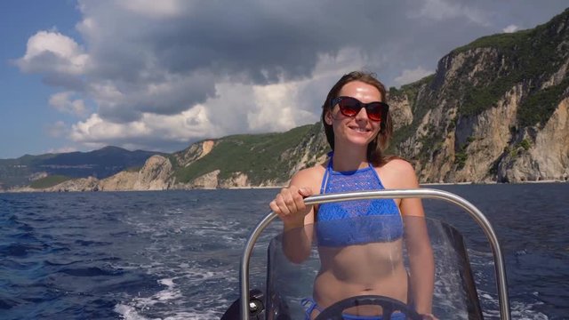 Summer vacation - young girl driving a motor boat on the sea