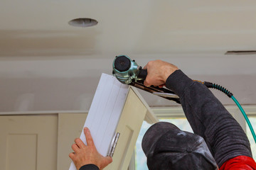 Worker using brad nail gun installs doors