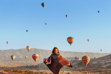 A tourist girl on a mountain top enjoying wonderful view of the sunrise and balloons in Cappadocia....