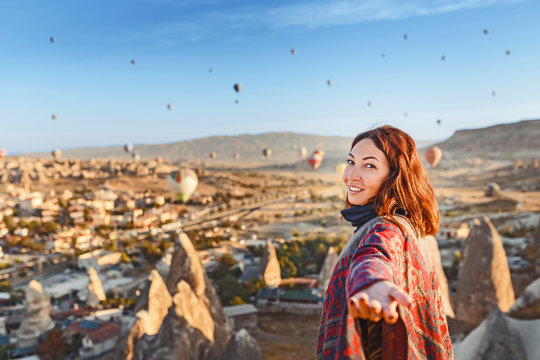 Woman watching at colorful hot air balloons flying over the valley at Cappadocia. Follow me and travel in Turkey concept
