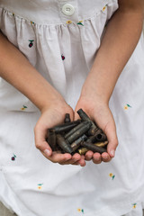 Little girl holding rifle bullets shell in her hands close up