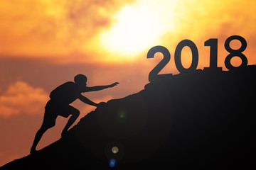 Silhouette of man hiking mountain to 2018 word at sky sunset, concept Happy New year