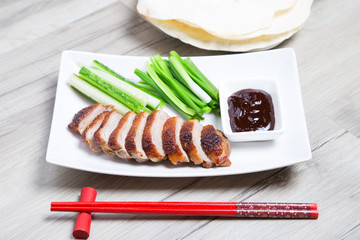 Baked duck with hoisin sauce, pancakes, cucumbers and shallots. Selective focus, close-up.
