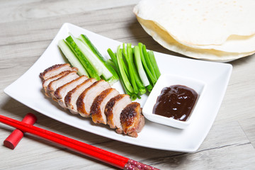 Baked duck with hoisin sauce, pancakes, cucumbers and shallots. Selective focus, close-up.