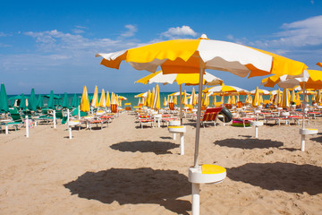 Adriatic Sea coast view. Seashore of Italy, summer umbrellas on sandy beach with clouds on horizon.