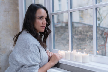 Frau an Fenster mit Kerzen