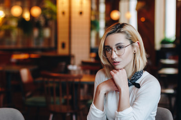 Portrait of beautiful woman in glasses in cafe