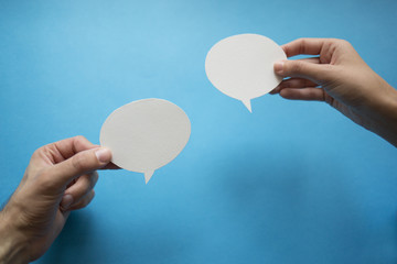 Hands holding an empty speech balloon.