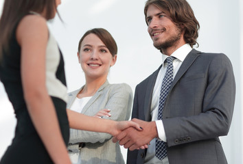 Businesspeople  shaking hands against room with large window loo