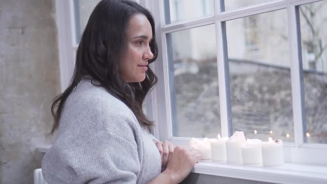 Frau schaut aus Fenster mit Kerze