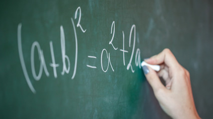 girl with chalk in her hand solves a mathematical problem on the blackboard